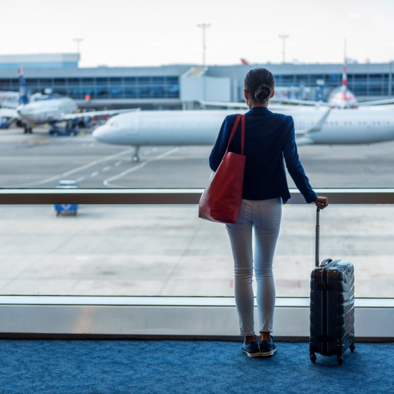 Woman at airport looking out the window at planes on the tarmac