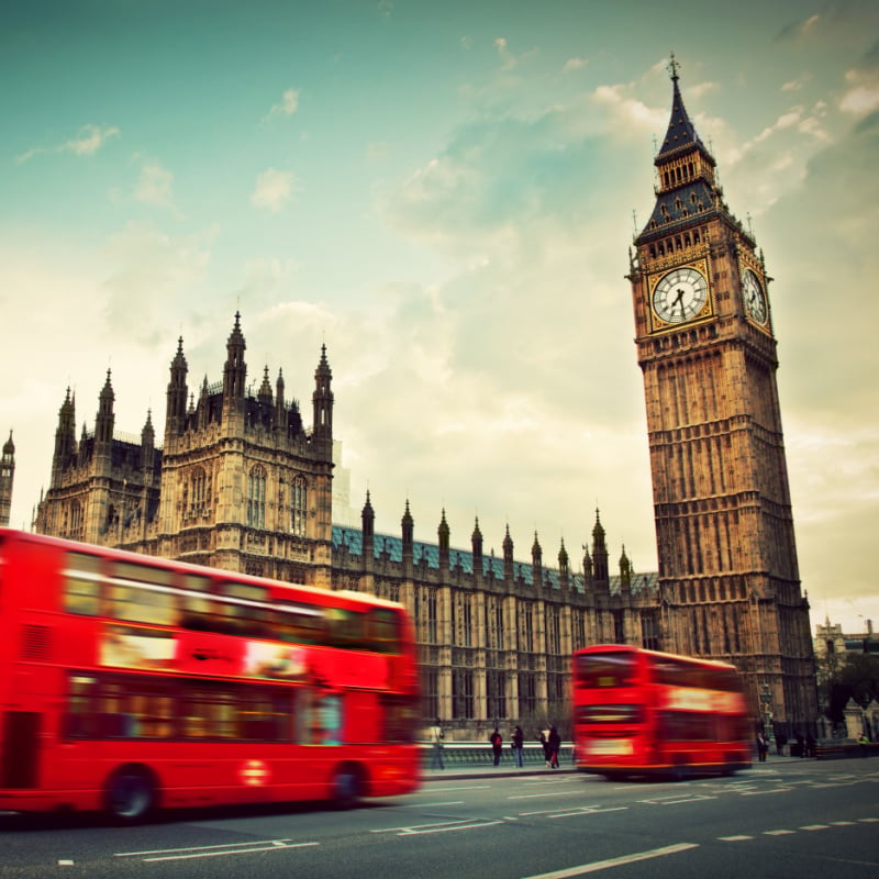 London, the UK. Red bus in motion and Big Ben, the Palace of Westminster.