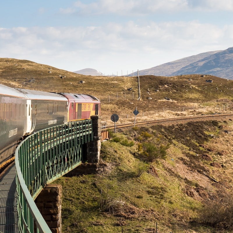 The Caledonian Sleeper train crosses Rannoch Viaduct on the scenic West Highland Line railway in the Scottish Highlands.