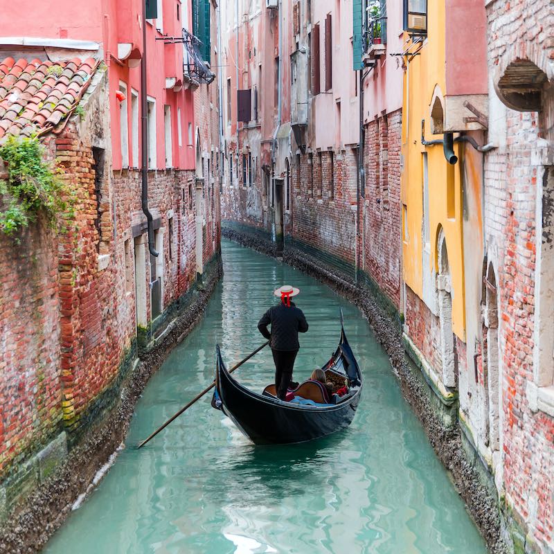 Venetian,Gondolier,Punting,Gondola,Through,Green,Canal,Waters,Of,Venice,