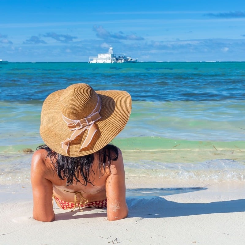 A Young Woman Sunbathing By The Caribbean Sea In Punta Cana, The Dominican Republic, Latin America