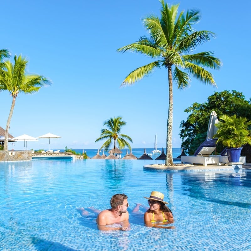 Couple Of Tourists Swimming In A Lagoon Style Pool In A Luxury Resort In Mauritius, East Africa