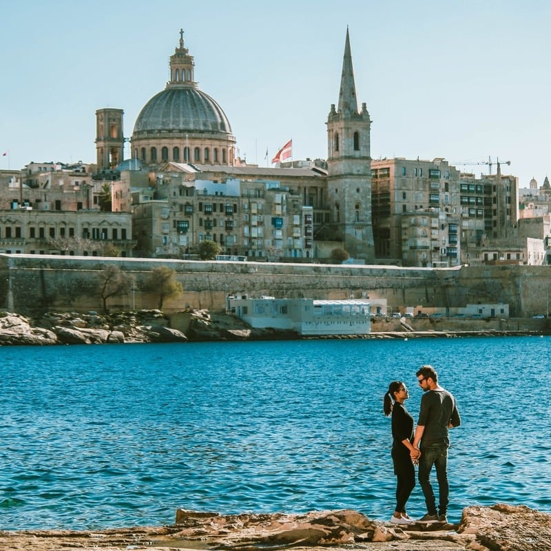 Young Couple Embracing Against The Backdrop Of Valletta, Capital Of Malta