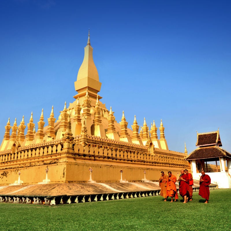 buddhist monks walk past wat phra that temple in vientiane laos