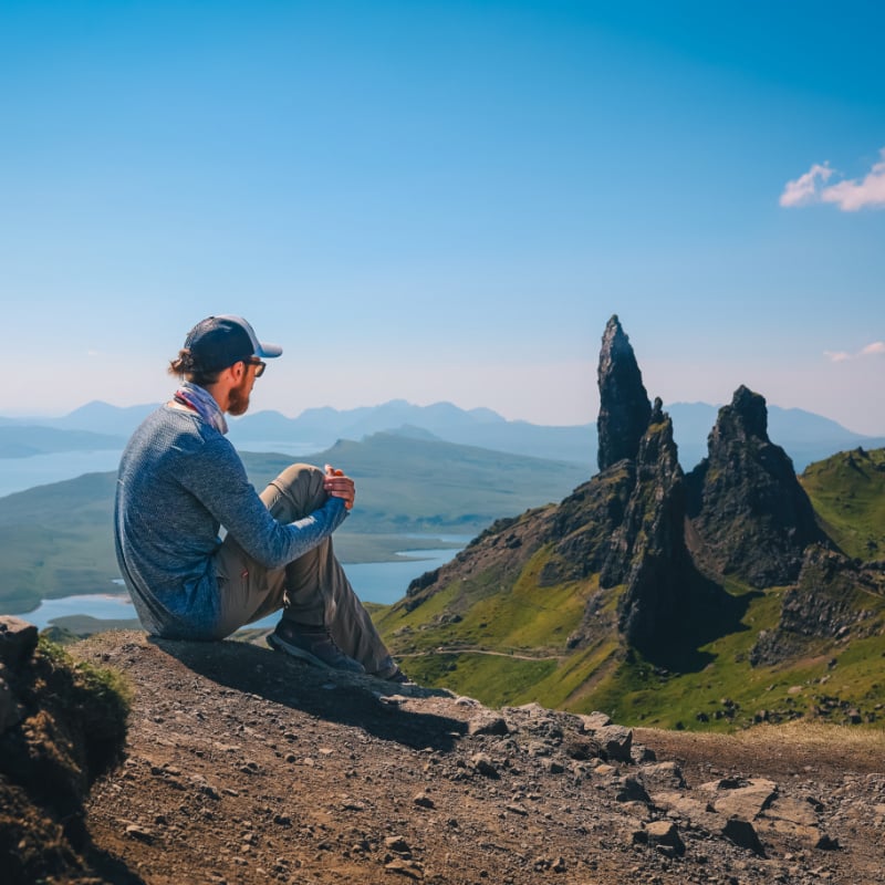 male traveler looks out at old man of storr on isle of skye scotland