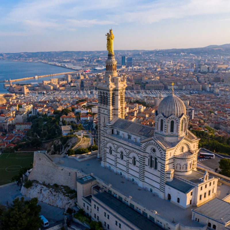 aerial view of basilica and city below in marseille france at golden sunset