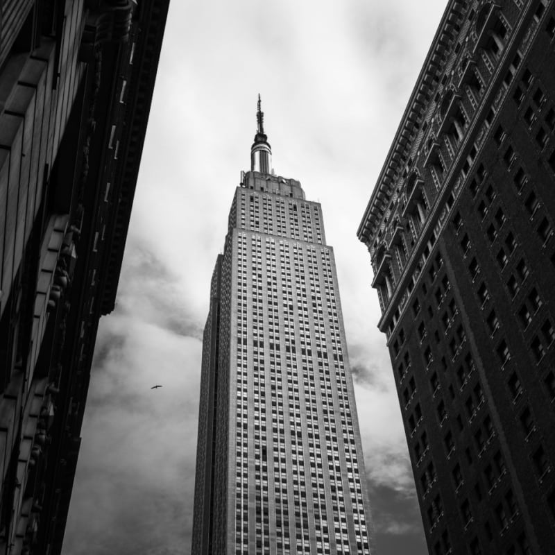 a black and white photo of the empire state building from street level