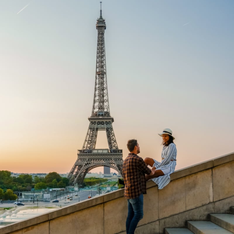 young couple sitting on stairs with the eiffel tower in the background in paris france