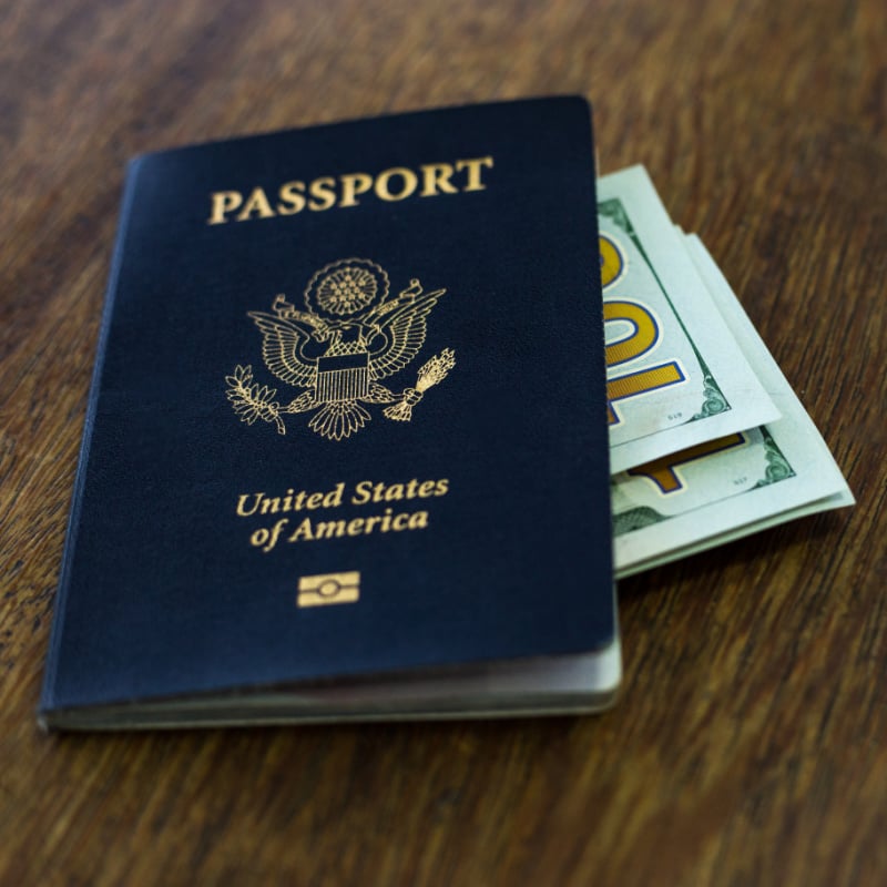 One American passport with some US dollars on top of a wooden table