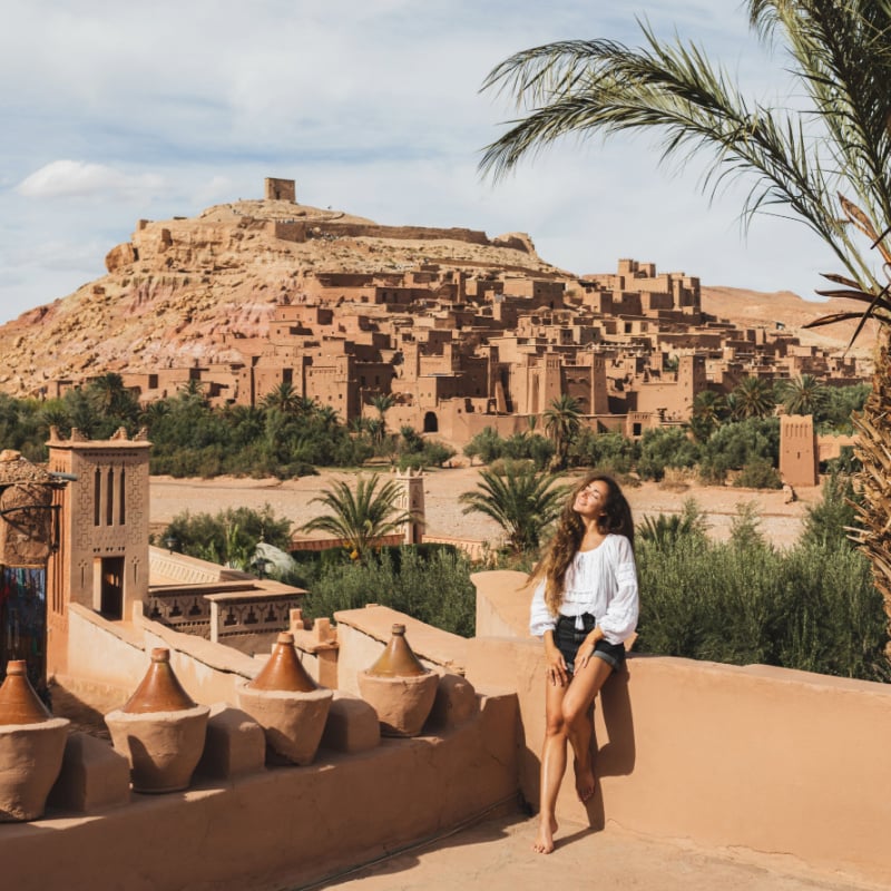 Beautiful young woman happy to travel in Morocco. Ait-Ben-Haddou kasbah on background