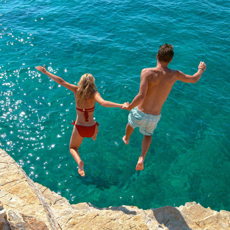 A Couple Jumping Together Into The Mediterranean, Southern Europe