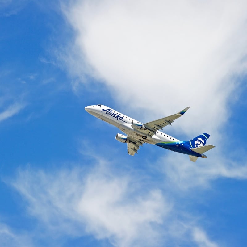 Alaska Airlines plane flying in blue sky