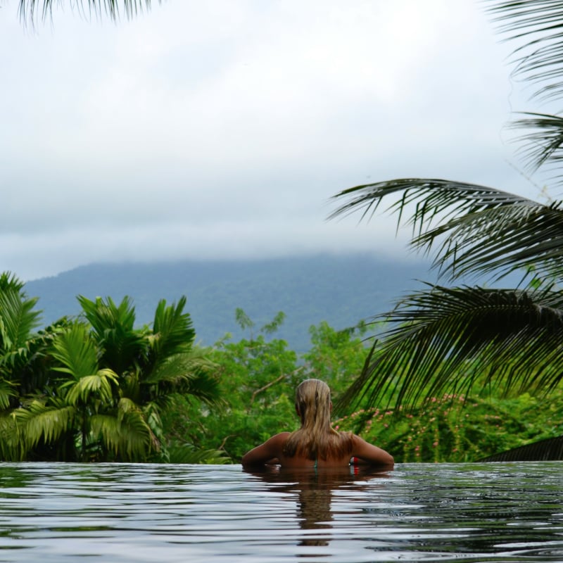 Solo travel in infinity pool overlooking Costa Rican jungle