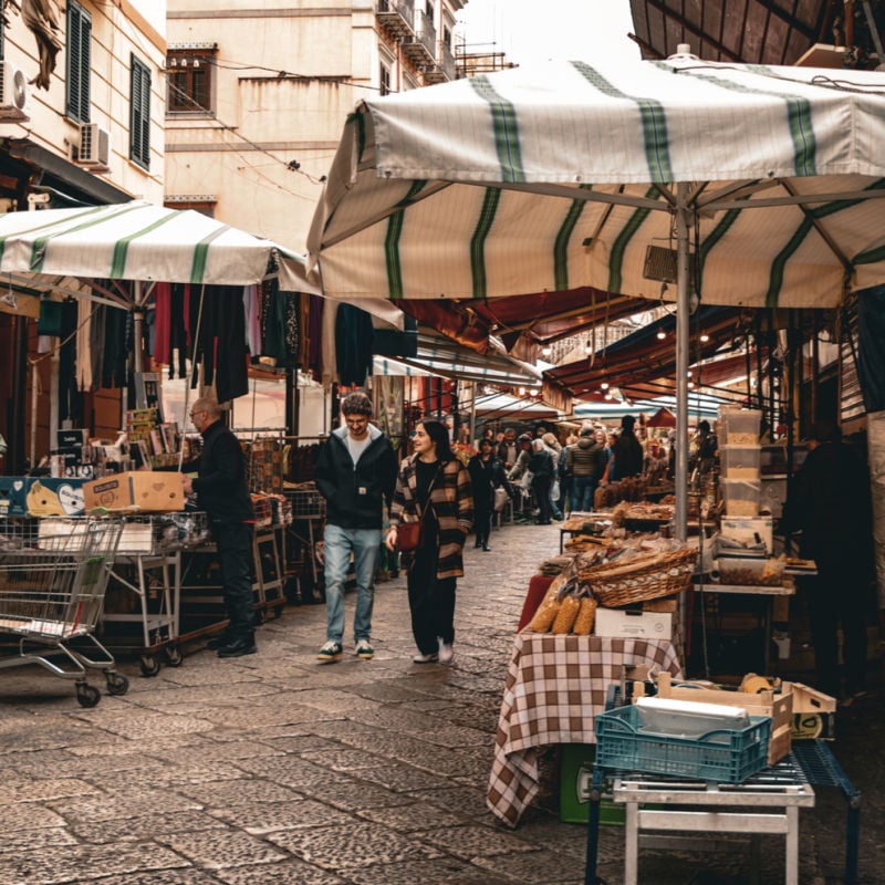 Couple walking through street market in Palermo