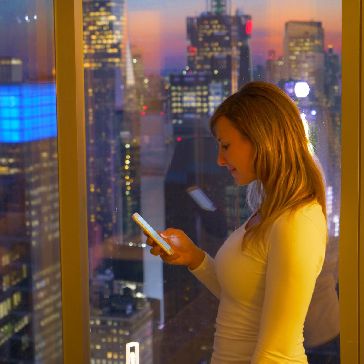 Woman in a hotel room overlooking Times Square, New York