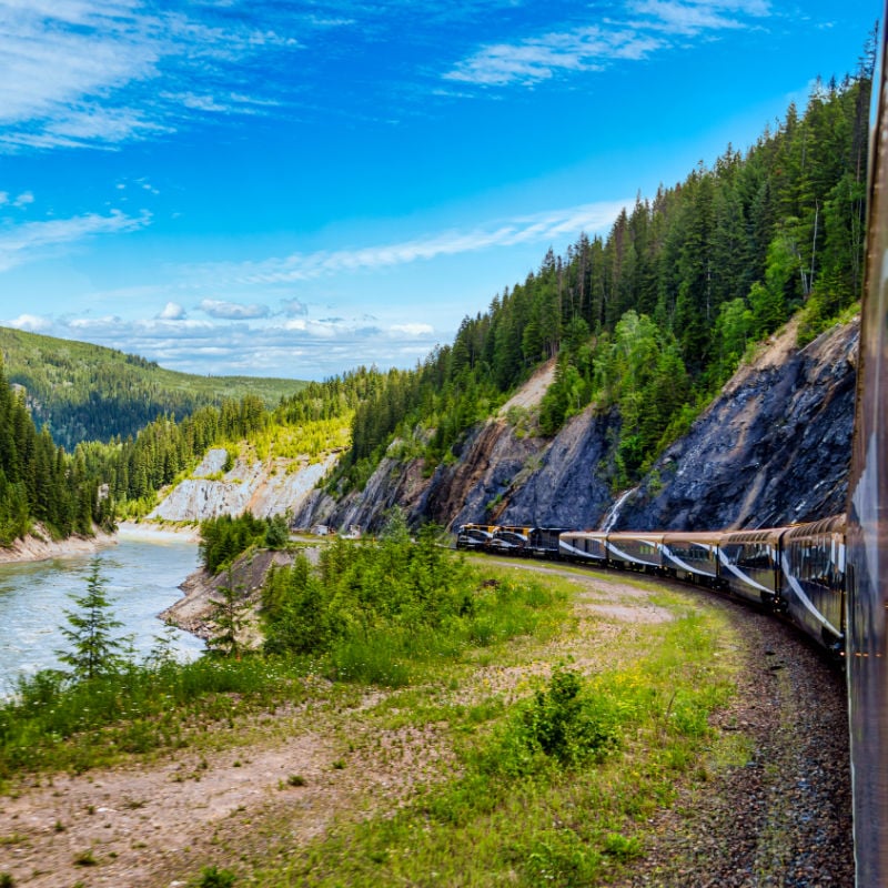 Rocky Mountain train passing river. 